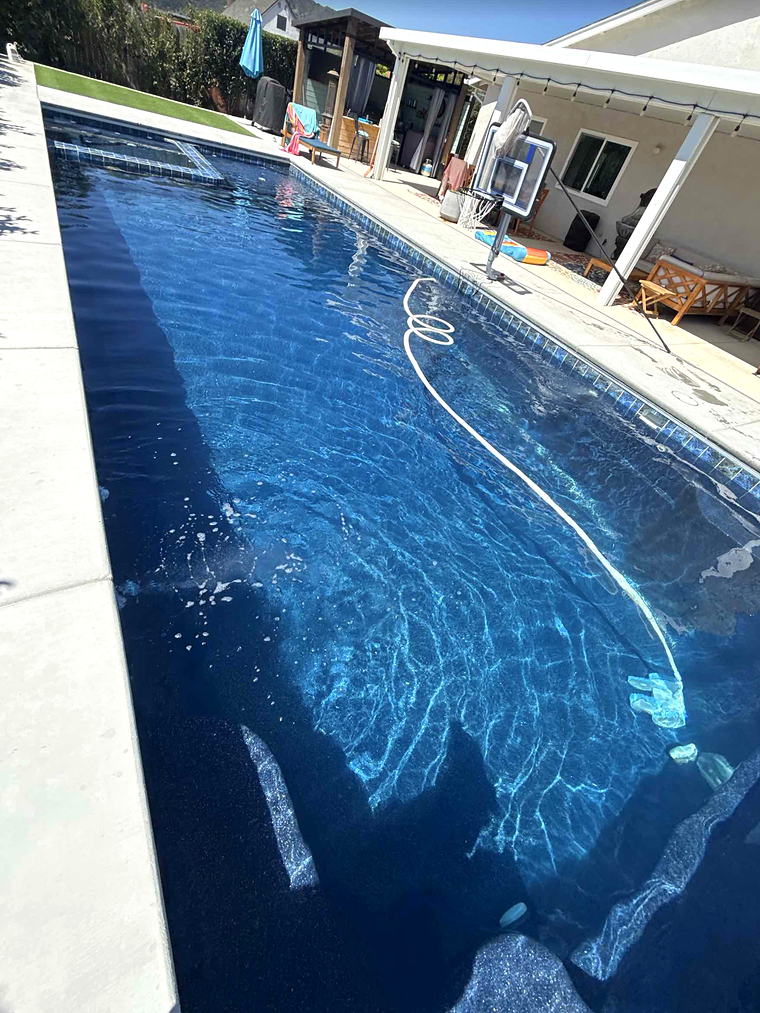 Full length view down a forty-foot Latham Astoria 16 fiberglass pool running alongside a covered patio